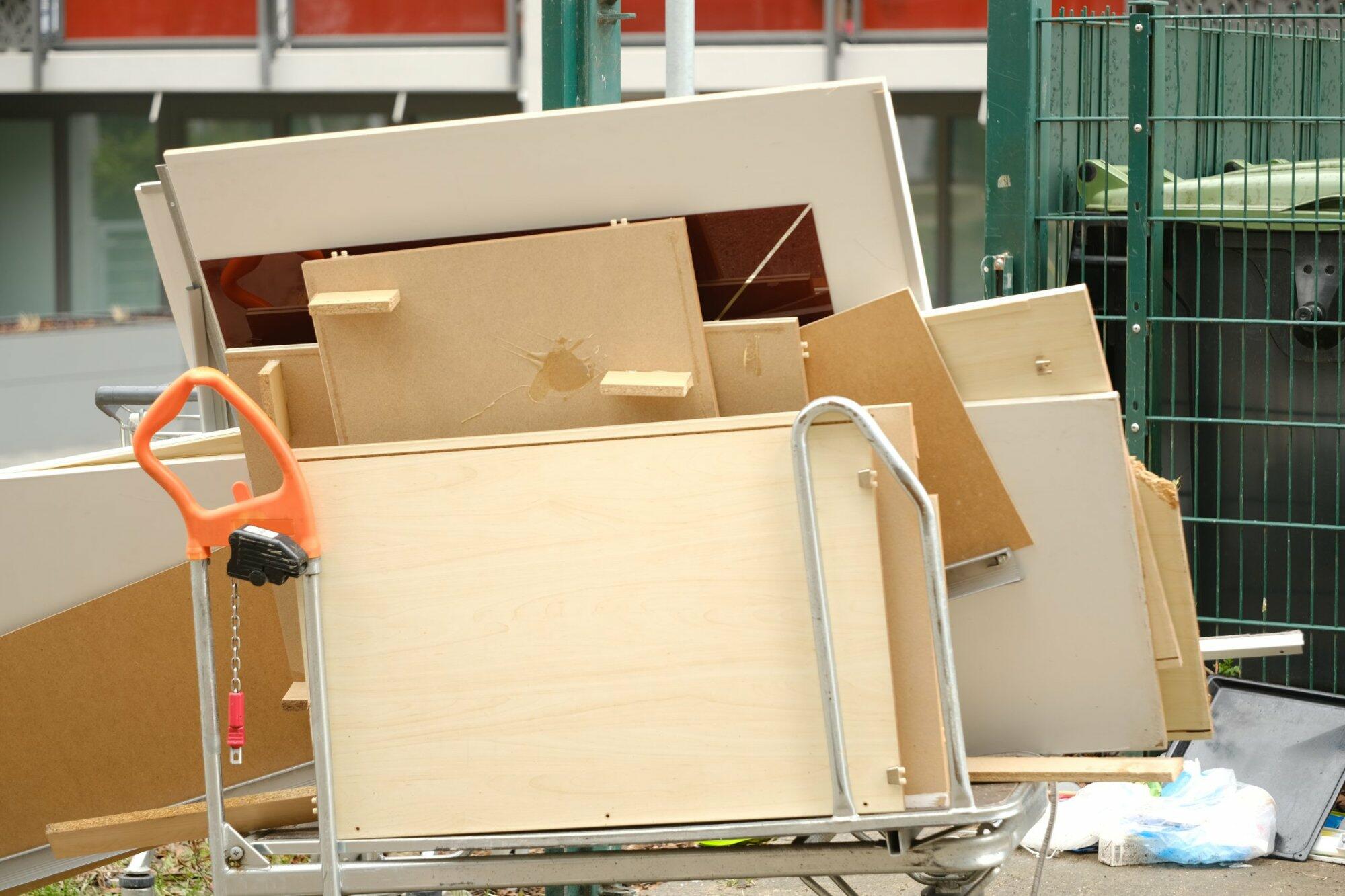 Sperrmüll mit alten Möbelteilen neben Müllcontainern